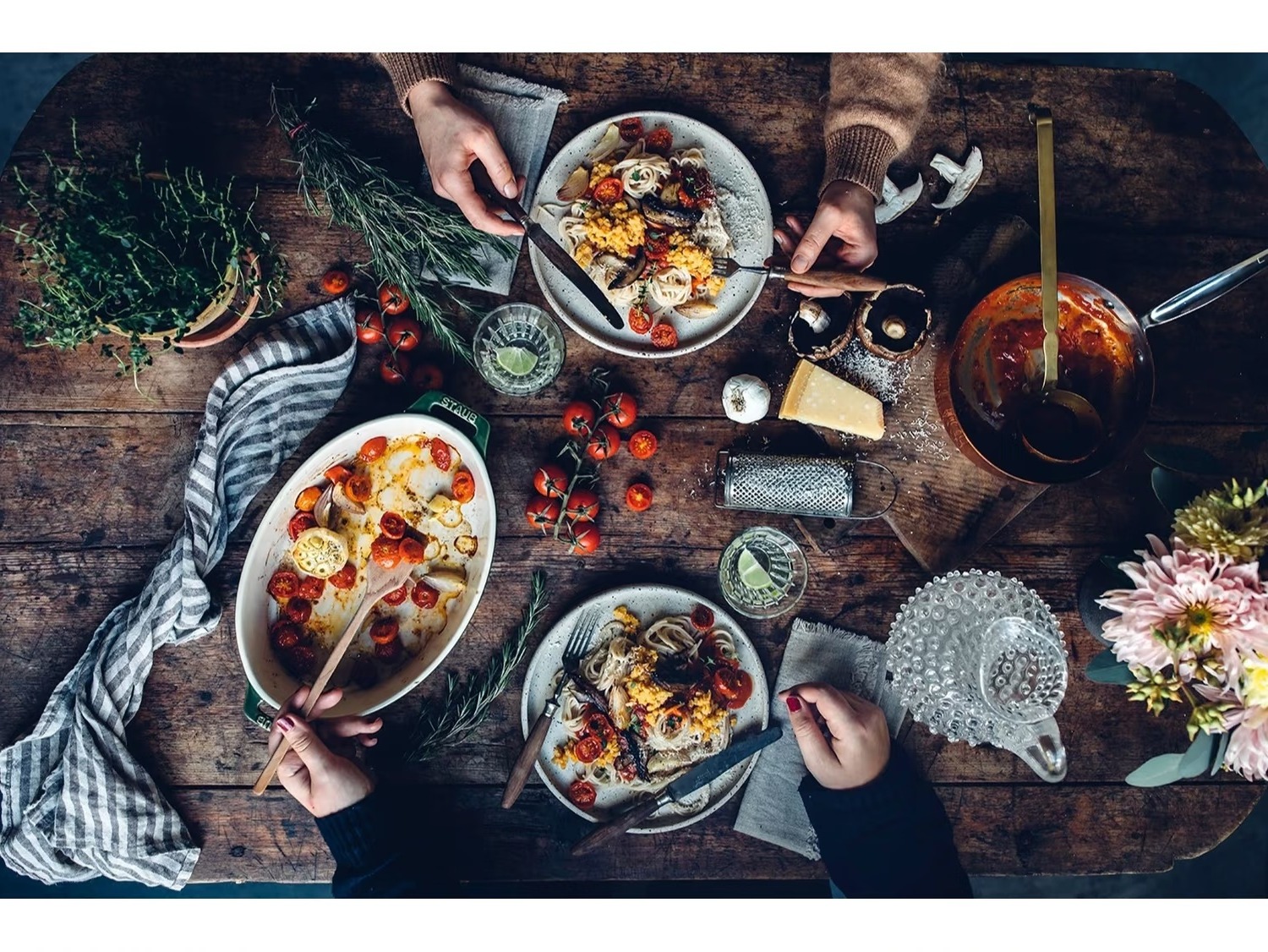 Overhead shot of a shared pasta dinner spread on a rustic wooden table